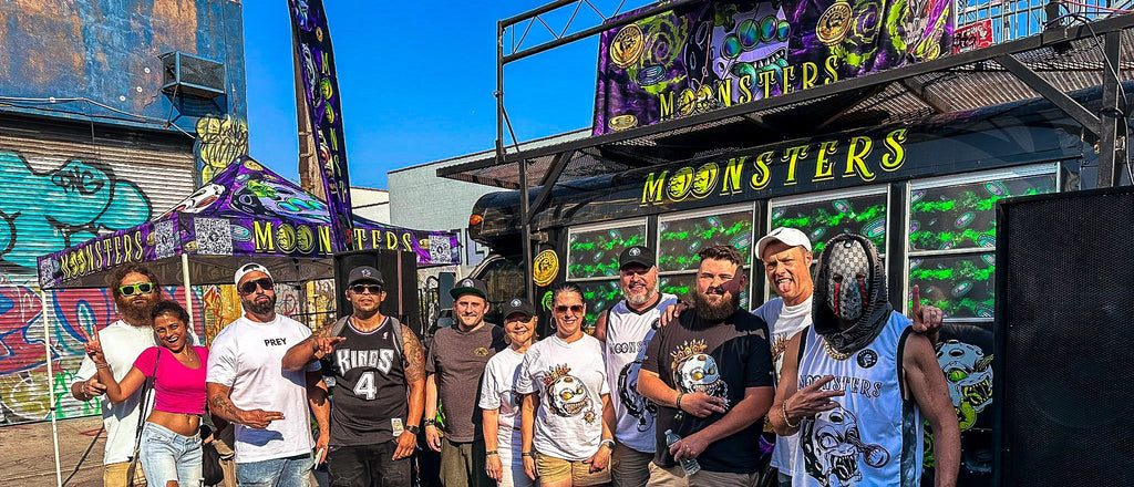 Group of people posing in front of the colorful Moonsters stage bus at Brooklyn NFT NYC event.