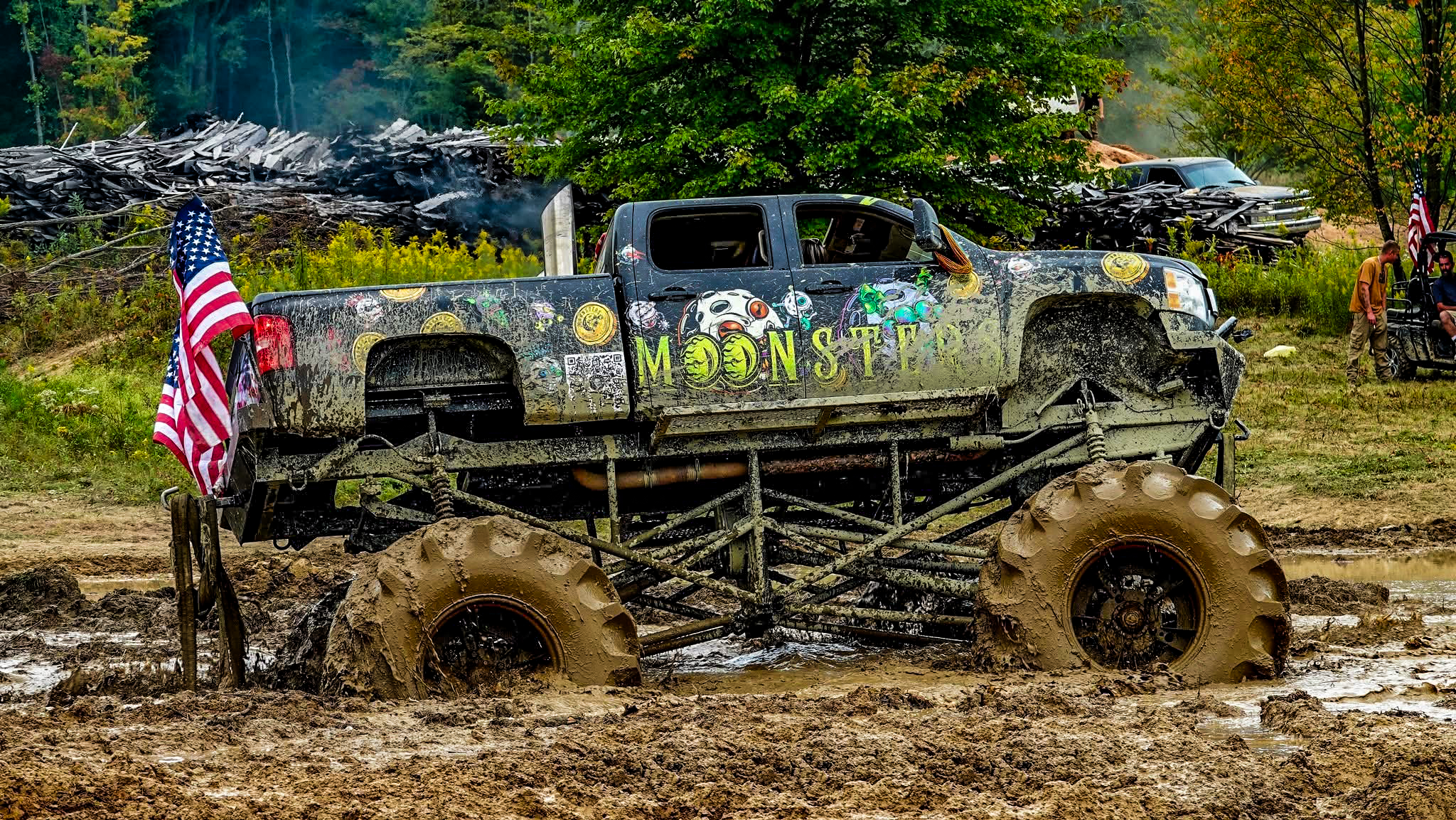 Muddy monster truck with MOONSTERS branding in a forested area