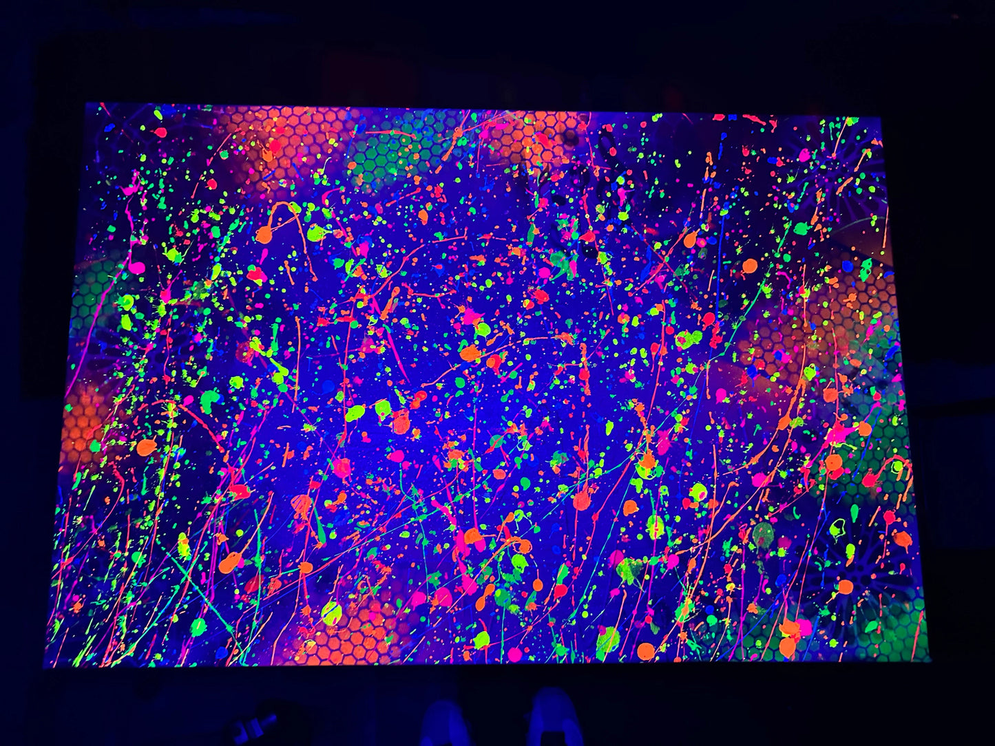 Abstract neon splattered artwork with vibrant green, orange, and blue streaks on a dark background.