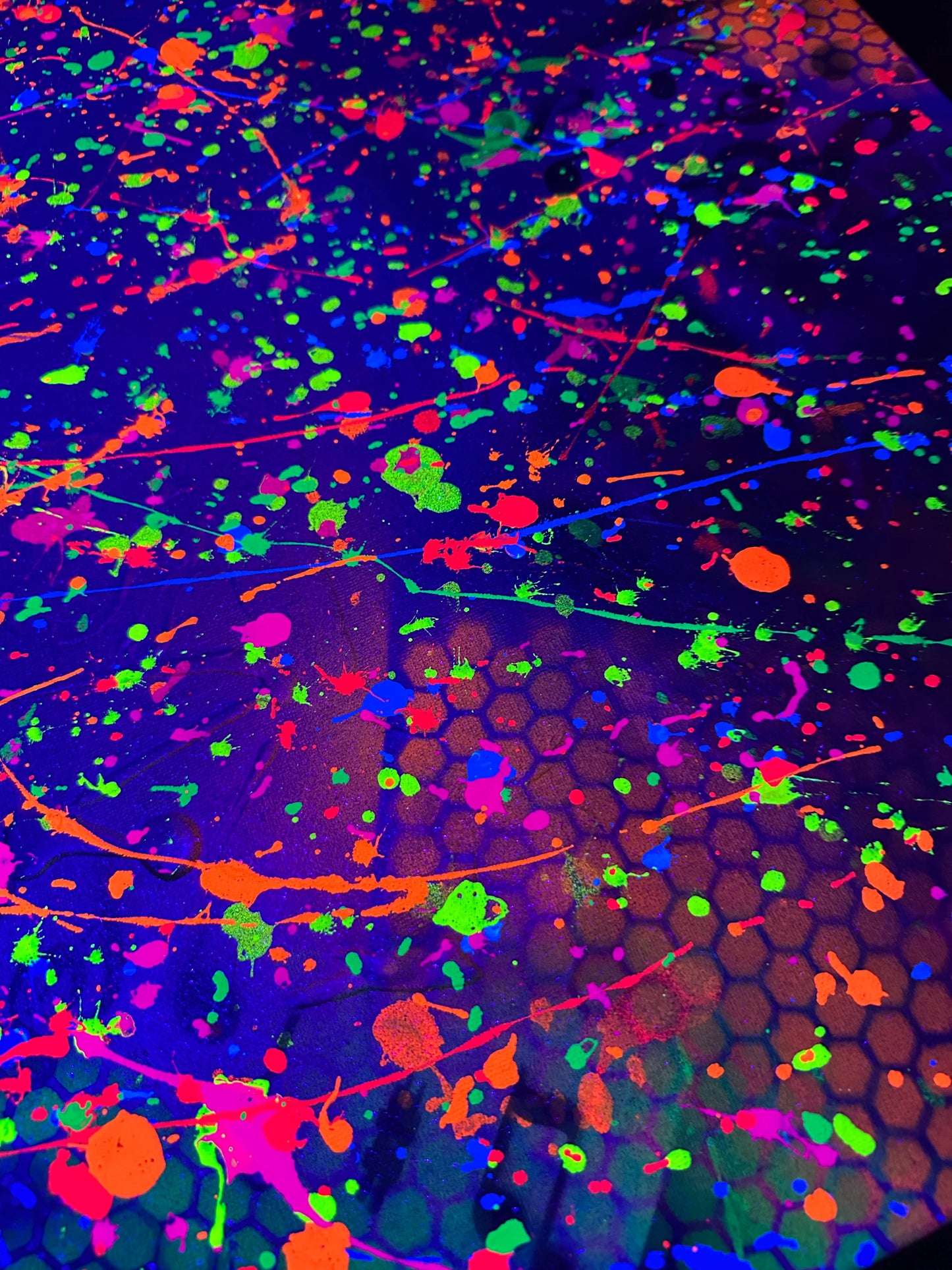 Abstract artwork with vibrant neon splashes of orange, green, and pink over dark hexagonal patterns.