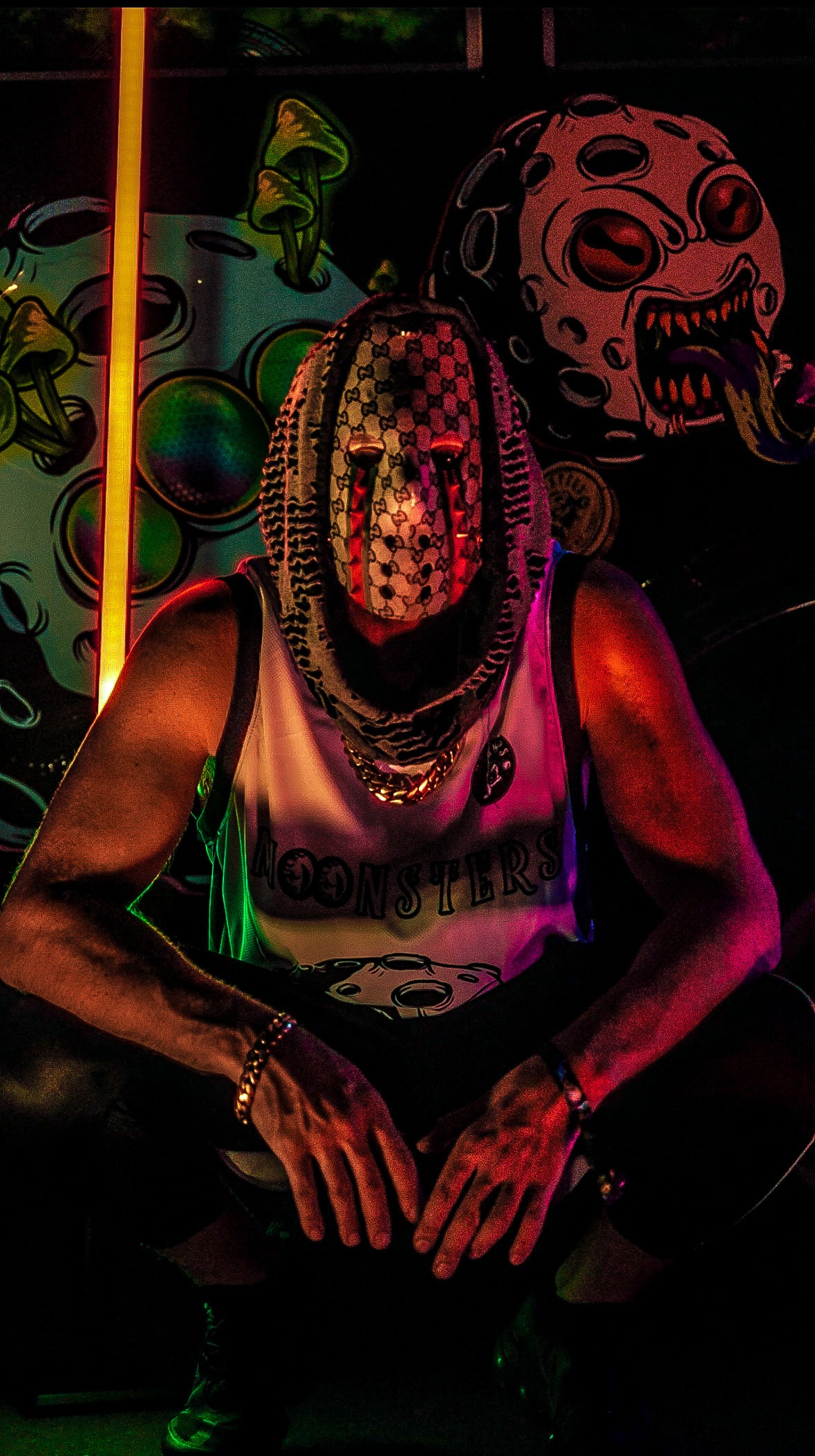The Sol Saver wearing a Gucci ski mask with intricate designs in a dark setting.